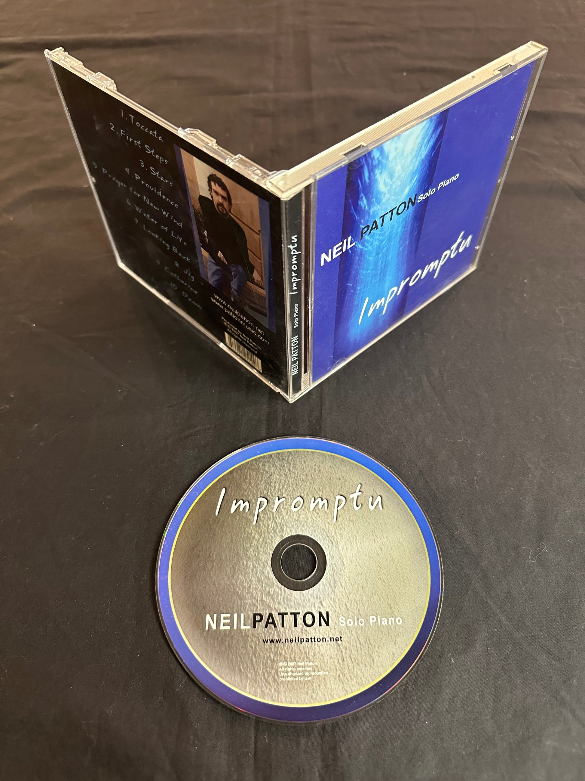 An image of the Impromptu Compact Disc lying next to an open CD jewel case displaying the front and back covers of the album.